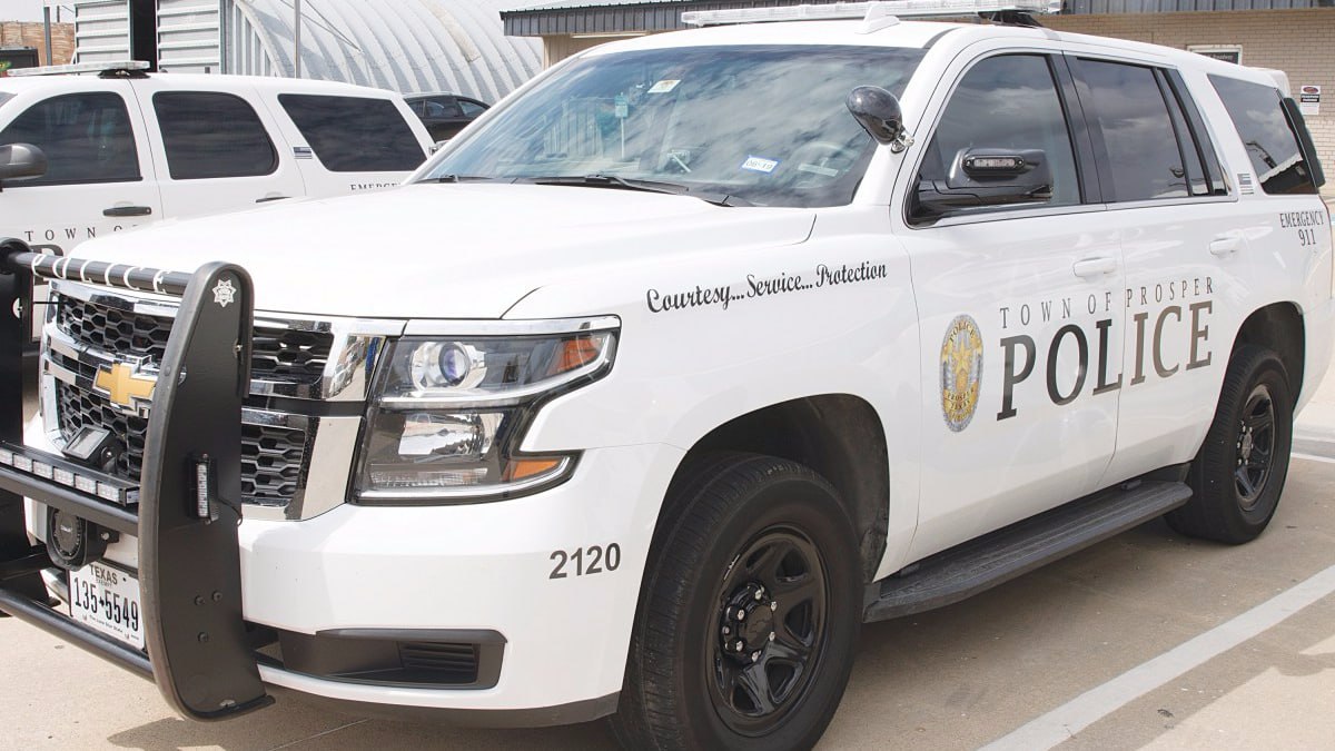 A white Town of Prosper Police Tahoe patrol vehicle in a parking lot.
